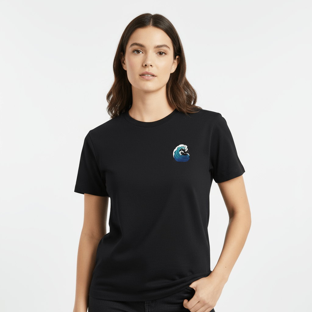 Femme portant un t-shirt noir BRISURE avec une petite vague bleue imprimée sur la poitrine.